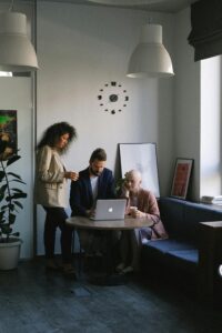 This is an image of three people gathered around a laptop.