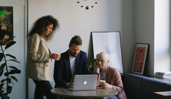 This is an image of three people gathered around a laptop.